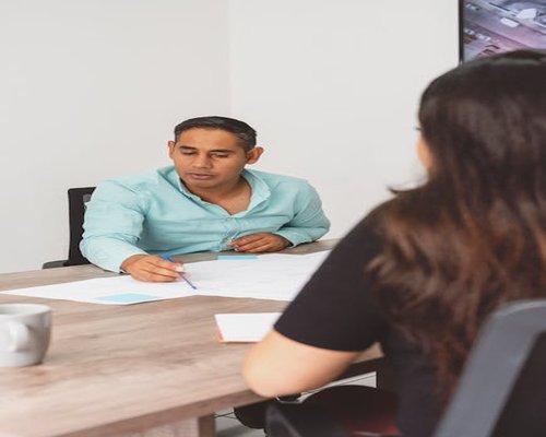 Equipo de trabajo en una mesa conversando sobre bienestar en la oficina